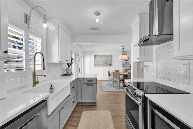 5205 Saint Regis Pl, Belle Isle, FL 32812 - kitchen with tasteful backsplash, visible vents, wall chimney exhaust hood, a sink, and appliances with stainless steel finishes