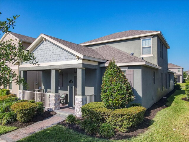 9432 Komika Ln, Winter Garden, FL 34787 - view of front of house featuring covered porch, roof with shingles, stucco siding, and a front yard