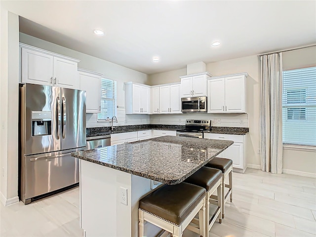 9432 Komika Ln, Winter Garden, FL 34787 - kitchen featuring a center island, a kitchen bar, stainless steel appliances, white cabinetry, and baseboards