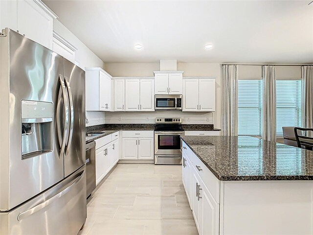 9432 Komika Ln, Winter Garden, FL 34787 - kitchen with a center island, dark stone counters, white cabinetry, appliances with stainless steel finishes, and recessed lighting