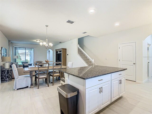 9432 Komika Ln, Winter Garden, FL 34787 - kitchen with dark stone countertops, visible vents, arched walkways, white cabinets, and a kitchen island
