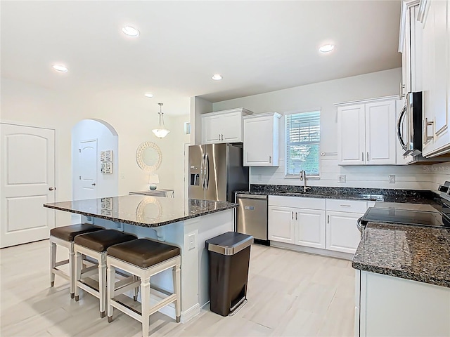 9432 Komika Ln, Winter Garden, FL 34787 - kitchen featuring a sink, white cabinetry, arched walkways, a center island, and appliances with stainless steel finishes