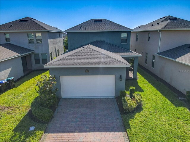 9432 Komika Ln, Winter Garden, FL 34787 - view of front facade with an attached garage, stucco siding, a shingled roof, decorative driveway, and a front yard