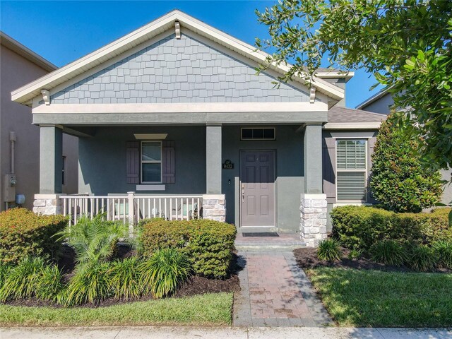 9432 Komika Ln, Winter Garden, FL 34787 - bungalow-style home with stone siding, stucco siding, and covered porch