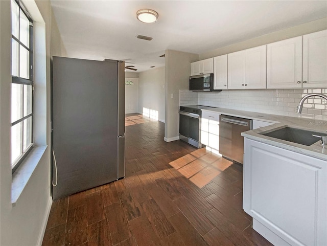 701 71st Ave N, Saint Petersburg, FL 33702 - kitchen featuring stainless steel appliances, a sink, baseboards, tasteful backsplash, and dark wood-style flooring