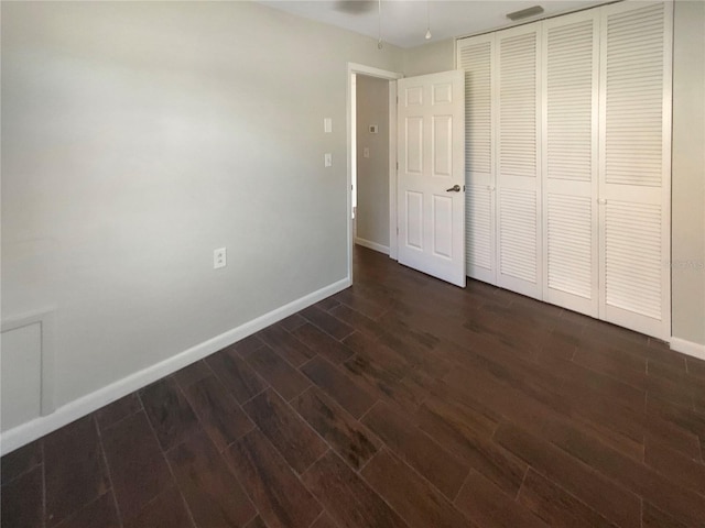 701 71st Ave N, Saint Petersburg, FL 33702 - unfurnished bedroom with dark wood-type flooring, baseboards, and a closet