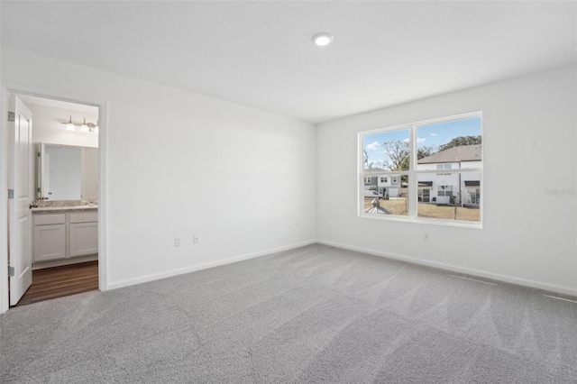 unfurnished bedroom with connected bathroom, baseboards, and carpet flooring