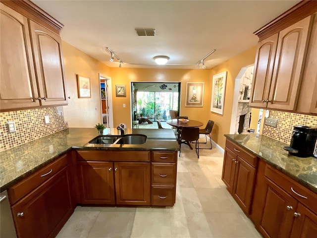 913 Red Fox Rd, Altamonte Springs, FL 32714 - kitchen with rail lighting, a sink, a peninsula, backsplash, and dark stone counters