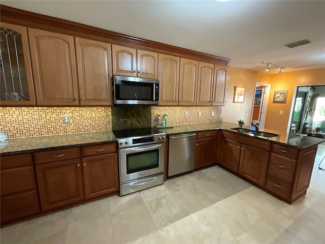 913 Red Fox Rd, Altamonte Springs, FL 32714 - kitchen with appliances with stainless steel finishes, rail lighting, a peninsula, tasteful backsplash, and dark stone countertops