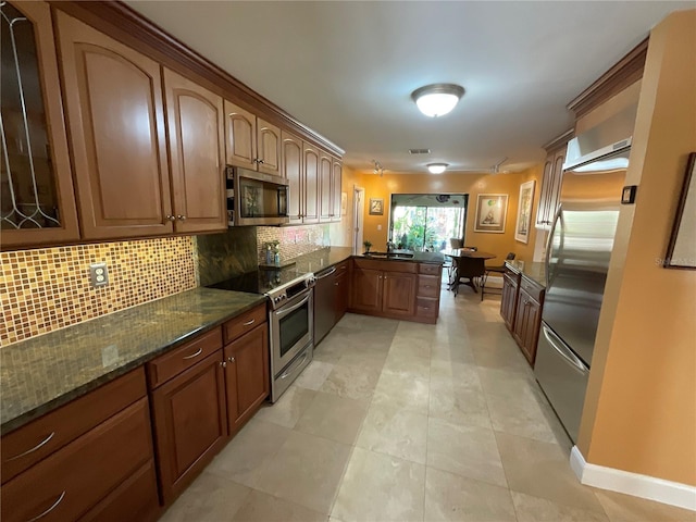 913 Red Fox Rd, Altamonte Springs, FL 32714 - kitchen featuring stainless steel appliances, a peninsula, tasteful backsplash, dark stone counters, and brown cabinets