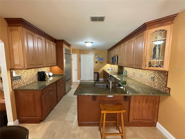 913 Red Fox Rd, Altamonte Springs, FL 32714 - kitchen featuring stainless steel appliances, a peninsula, glass insert cabinets, decorative backsplash, and a kitchen bar