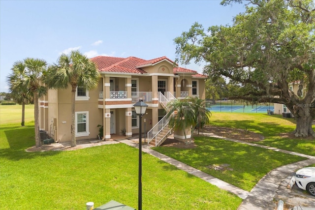 2808 Osprey Cove Pl Unit 201, Kissimmee, FL 34746 - view of front of house featuring stucco siding, stairway, a front lawn, and a tiled roof