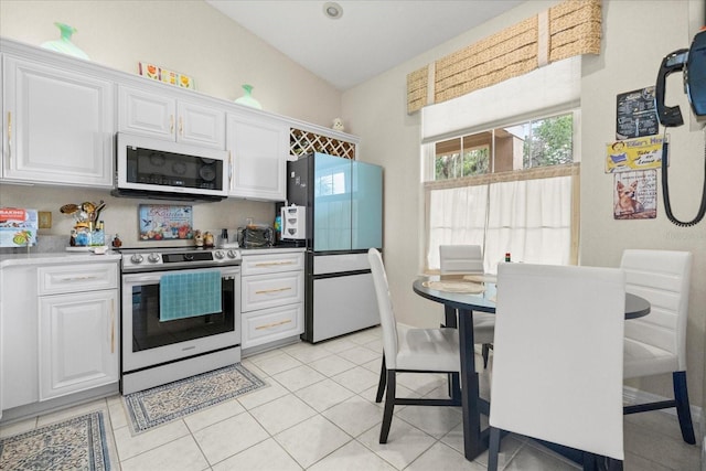 2808 Osprey Cove Pl Unit 201, Kissimmee, FL 34746 - kitchen with white microwave, stainless steel electric range oven, freestanding refrigerator, white cabinets, and lofted ceiling