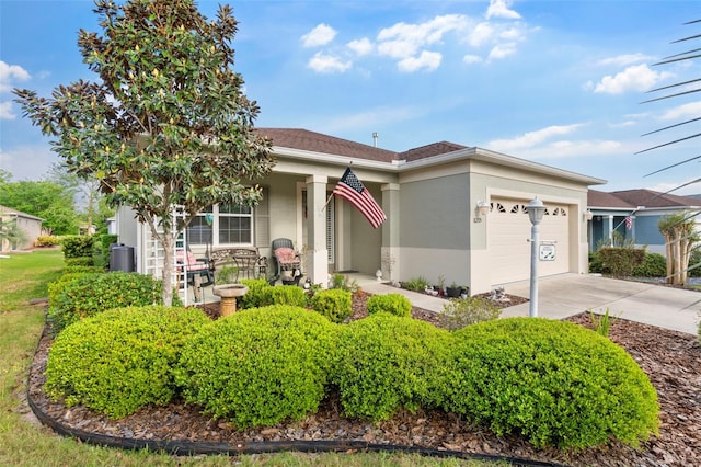 view of front facade featuring driveway, an attached garage, covered porch, and stucco siding
