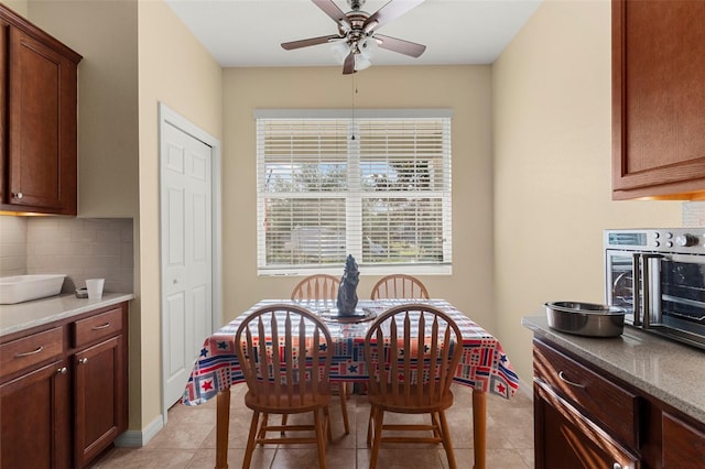 dining room with light tile patterned floors, a toaster, and a ceiling fan