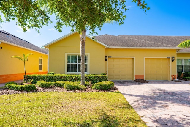 3205 Sonesta Ct Unit F, Clermont, FL 34711 - ranch-style house with a front yard, stucco siding, a shingled roof, decorative driveway, and a garage