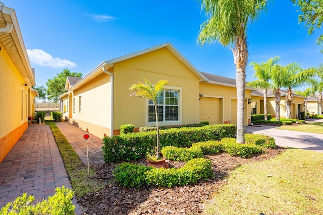 3205 Sonesta Ct Unit F, Clermont, FL 34711 - view of side of property featuring driveway, stucco siding, a garage, and roof with shingles
