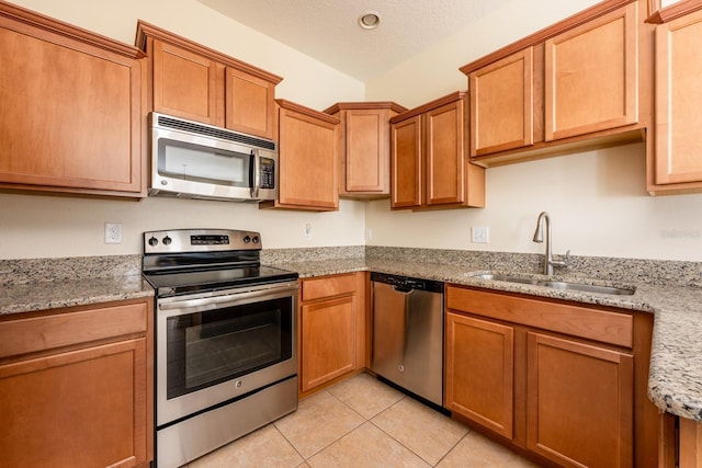 3205 Sonesta Ct Unit F, Clermont, FL 34711 - kitchen with a sink, light stone countertops, a textured ceiling, light tile patterned floors, and stainless steel appliances