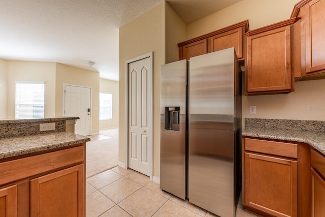 3205 Sonesta Ct Unit F, Clermont, FL 34711 - kitchen with stainless steel fridge, light stone countertops, light tile patterned flooring, and brown cabinets