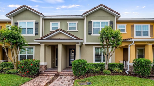 townhome / multi-family property featuring a porch, stucco siding, and a tiled roof