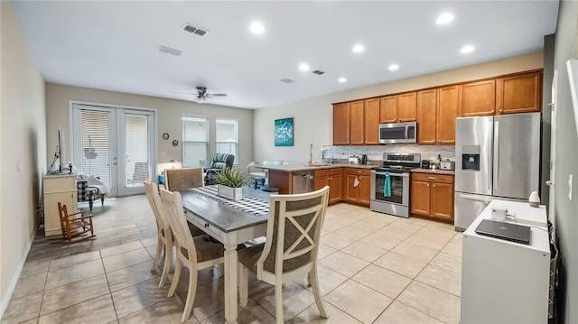 kitchen with light tile patterned floors, backsplash, visible vents, brown cabinetry, and stainless steel appliances