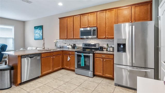 kitchen with a sink, brown cabinetry, and stainless steel appliances