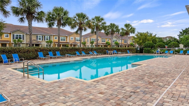 pool with a residential view, fence, and a patio