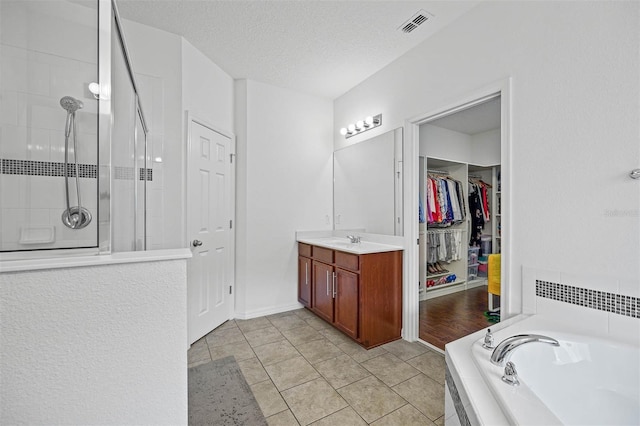 1802 Candlenut Cir, Apopka, FL 32712 - bathroom featuring visible vents, a bath, a textured ceiling, a shower stall, and vanity