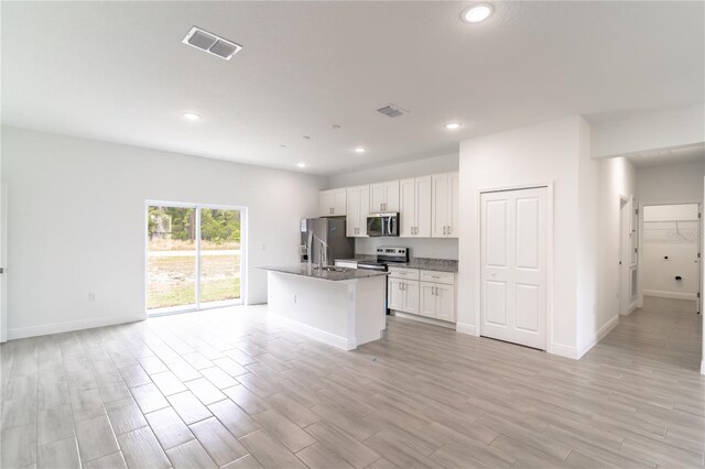 kitchen with visible vents, open floor plan, white cabinetry, stainless steel appliances, and light wood-style flooring