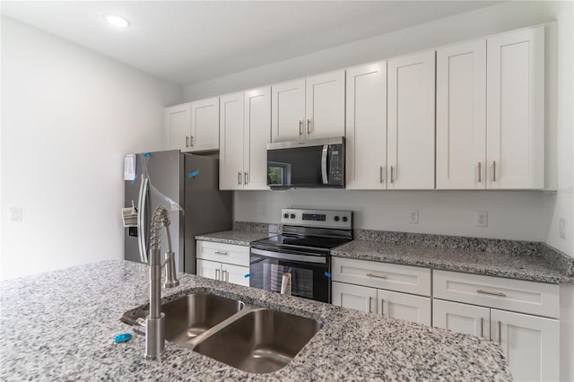 kitchen with a sink, white cabinets, light stone countertops, and stainless steel appliances