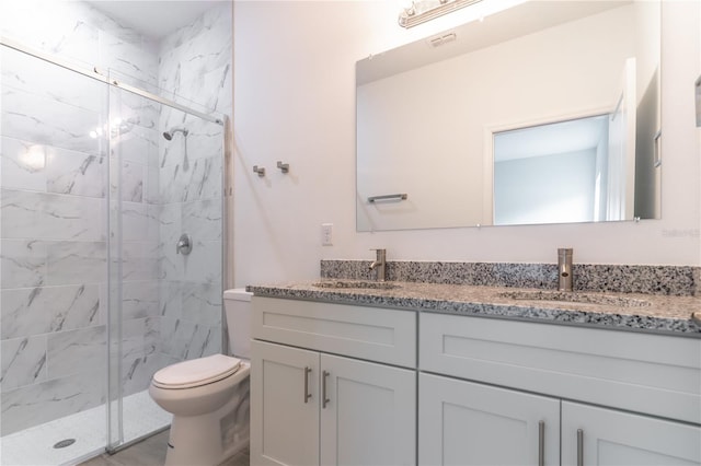 bathroom featuring double vanity, a marble finish shower, a sink, and toilet