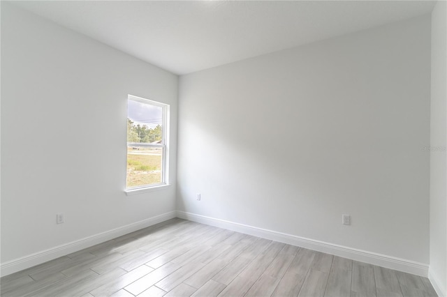 unfurnished room with baseboards and light wood-style floors