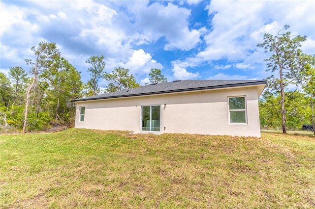 rear view of property featuring a yard and stucco siding