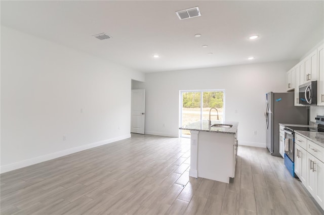 kitchen featuring an island with sink, white cabinets, visible vents, stainless steel appliances, and a sink