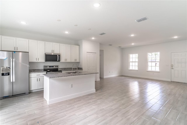 kitchen featuring a center island with sink, a sink, visible vents, and stainless steel appliances