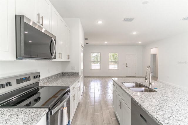 kitchen with recessed lighting, a sink, white cabinets, and stainless steel appliances