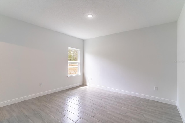 unfurnished room with light wood finished floors and baseboards
