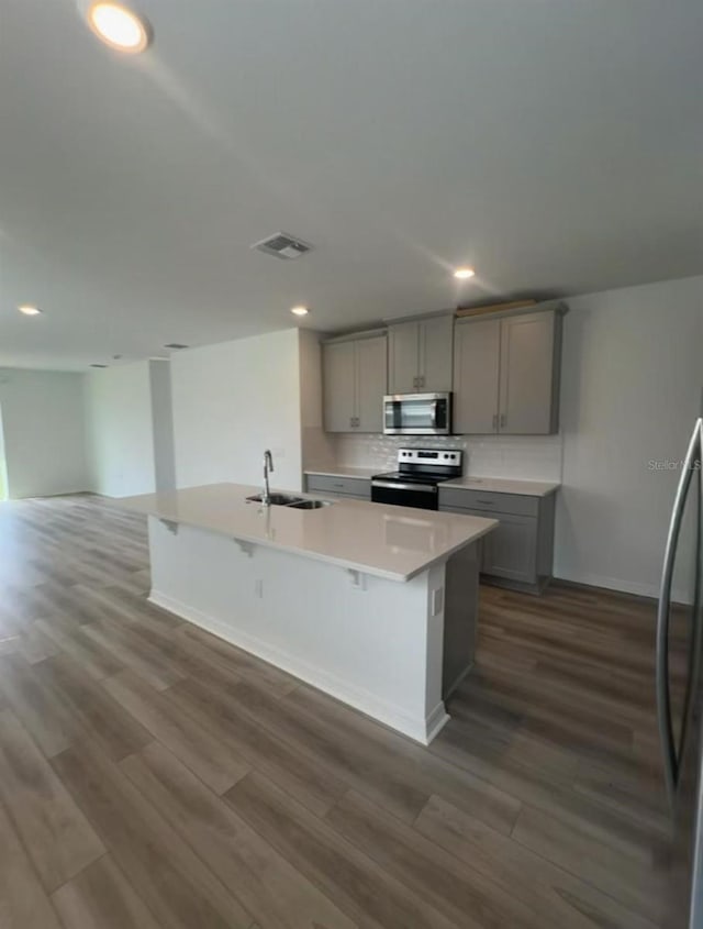 6028 Bimini Ave, Haines City, FL 33844 - kitchen featuring appliances with stainless steel finishes, gray cabinets, a sink, a center island with sink, and recessed lighting