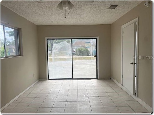 unfurnished room featuring light tile patterned floors, ceiling fan, a textured ceiling, and visible vents