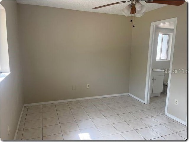 empty room featuring light tile patterned floors, baseboards, a ceiling fan, and a textured ceiling