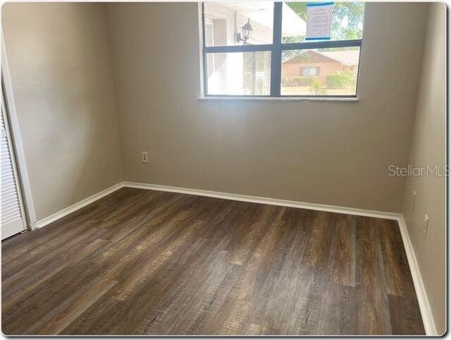 unfurnished room with baseboards and dark wood finished floors