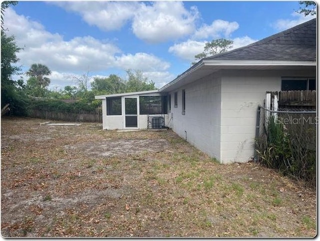 view of yard featuring fence, central air condition unit, and a sunroom
