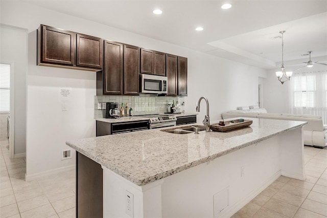 kitchen featuring open floor plan, appliances with stainless steel finishes, light tile patterned flooring, and dark brown cabinets