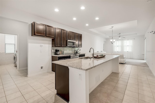 kitchen featuring light tile patterned floors, dark brown cabinets, recessed lighting, appliances with stainless steel finishes, and a sink