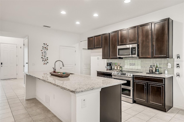 kitchen featuring light tile patterned flooring, visible vents, a center island with sink, stainless steel appliances, and a sink
