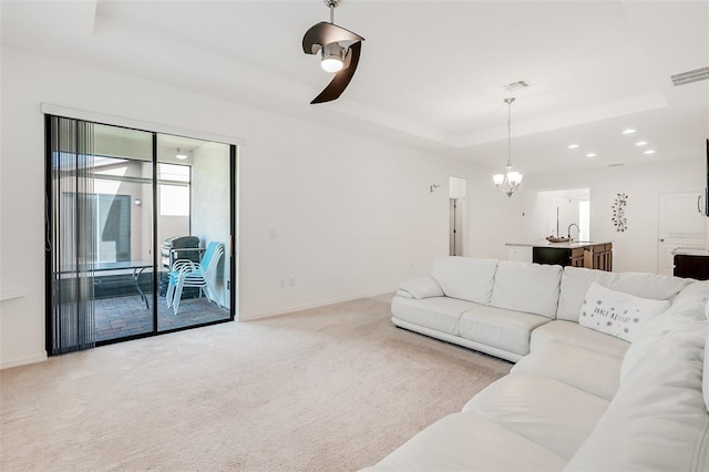 living area with a tray ceiling, baseboards, carpet flooring, and visible vents