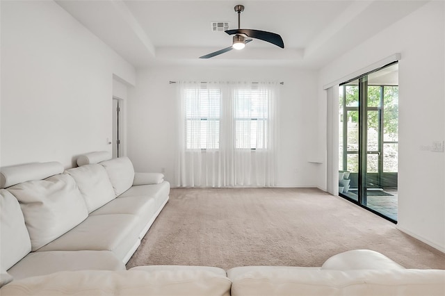 carpeted living area featuring visible vents, ceiling fan, and a tray ceiling