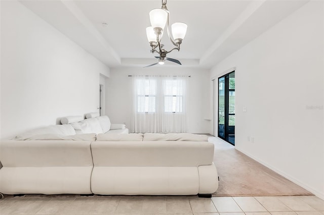 living room featuring light tile patterned floors, baseboards, a chandelier, a tray ceiling, and light colored carpet
