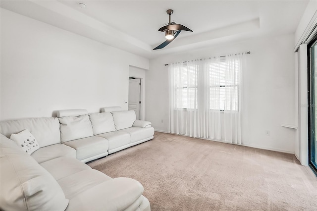carpeted living room with baseboards, a ceiling fan, and a raised ceiling