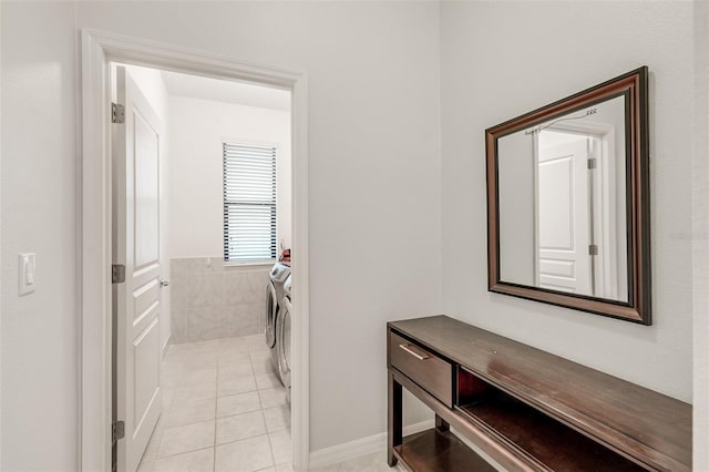 clothes washing area with laundry area, washing machine and clothes dryer, and light tile patterned floors